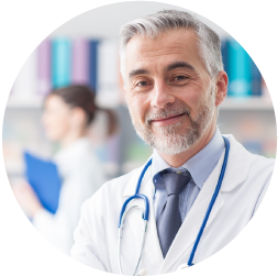 Smiling male doctor with gray hair and stethoscope in a medical office.