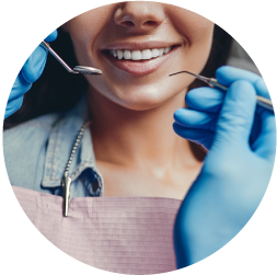 Dentist examining a smiling patient's teeth with dental tools.